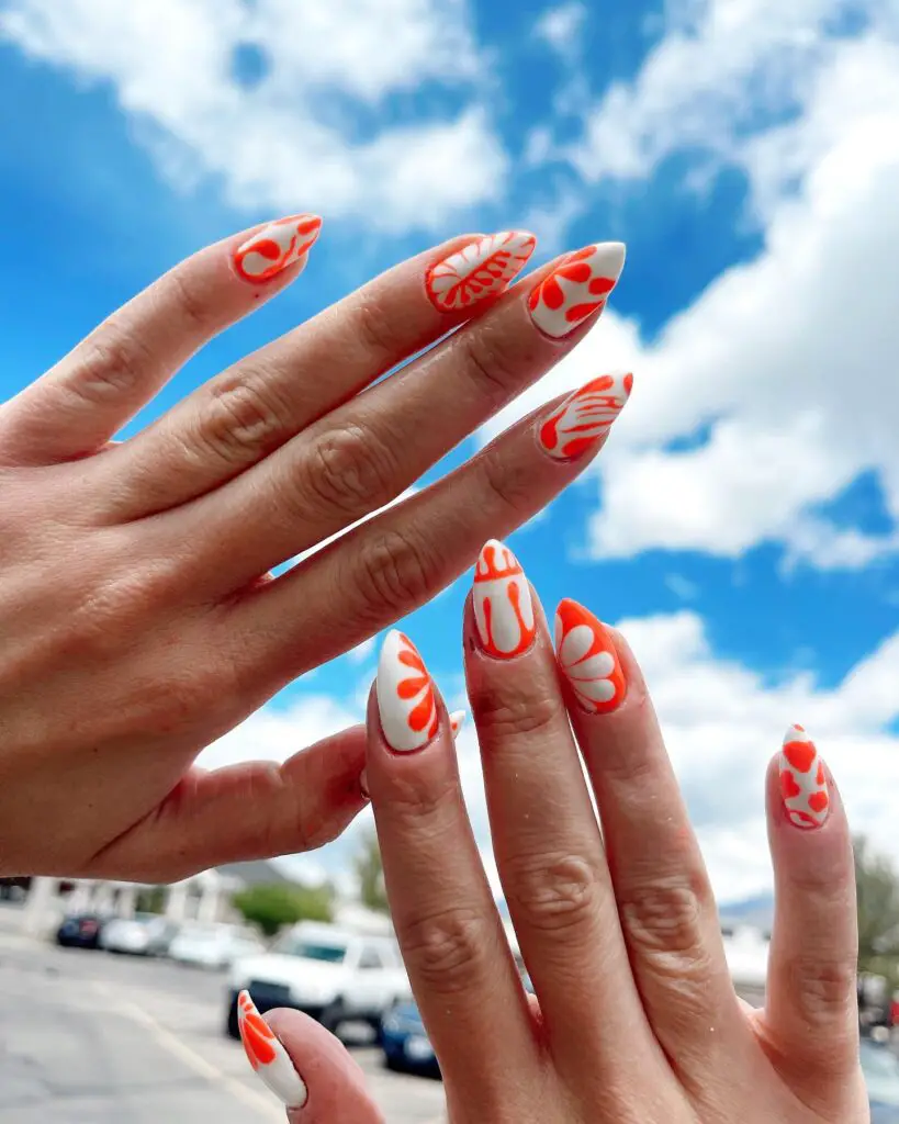 Vibrant orange swirls and abstract patterns on a white nail base, reflecting a playful and energetic summer nail art design.
