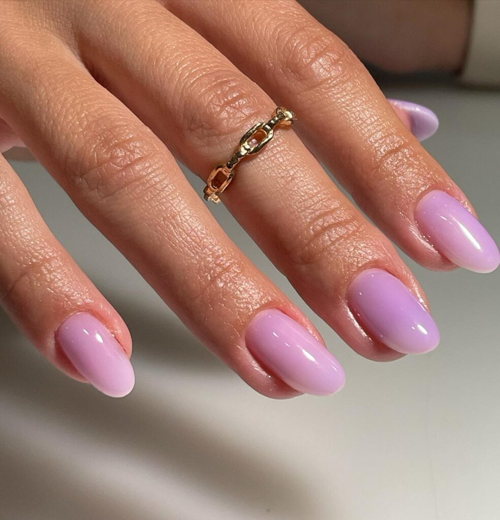 Elegantly manicured nails in a glossy lilac shade, aligned with almond shapes, ideal for articles about sophisticated and timeless spring nail trends.