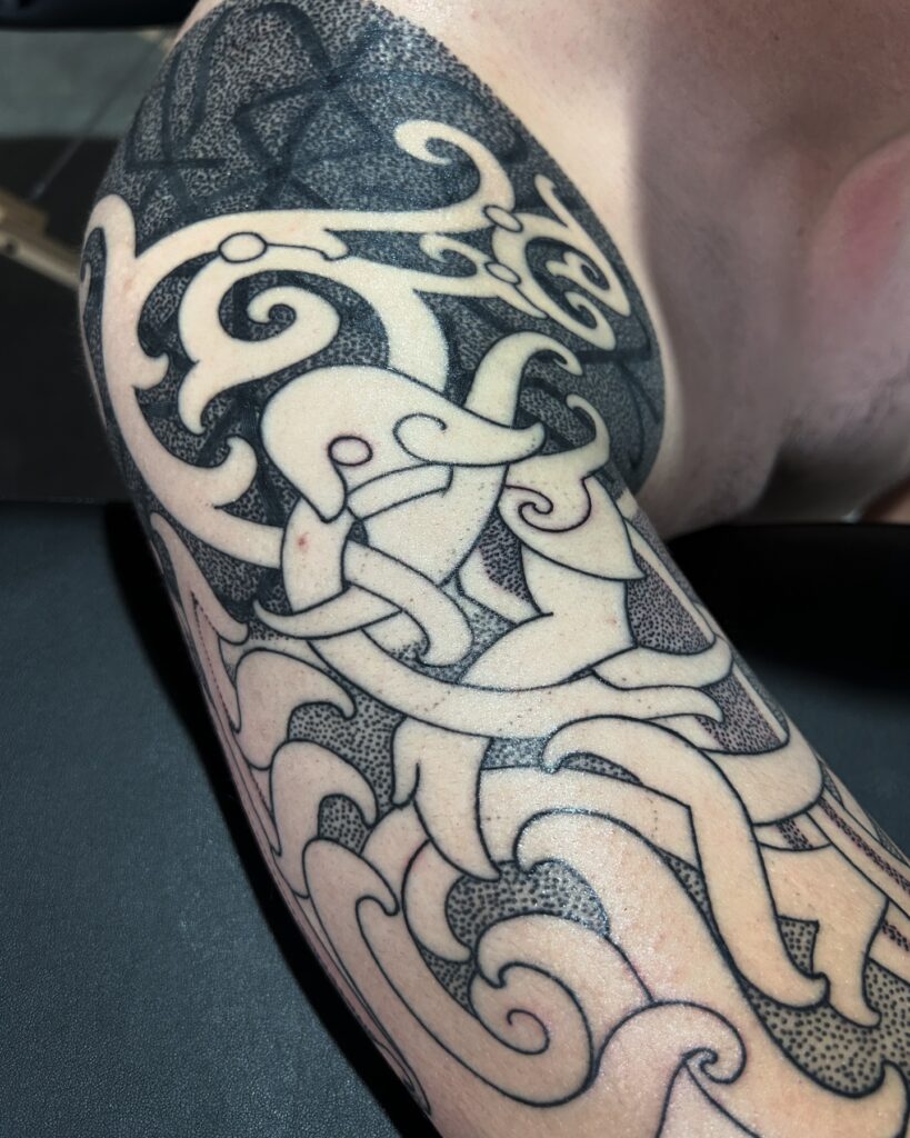 A shoulder tattoo with elegant Nordic swirls and dot work in black ink, representing Viking artistry.