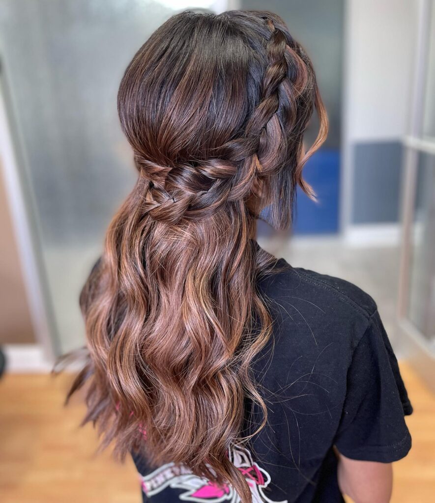 A side view of a woman's brunette hair styled in an elegant side braid with loose waves, perfect for a graceful prom look.