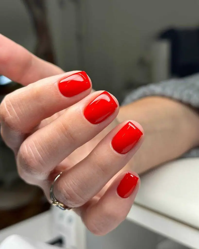 Short nails coated in a classic, glossy red polish, embodying timeless elegance and style.