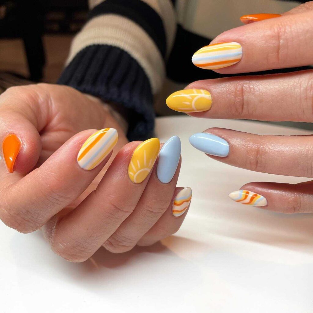 Oval nails with artistic swirls in white, yellow, and blue, reminiscent of the sun shining on a clear day.