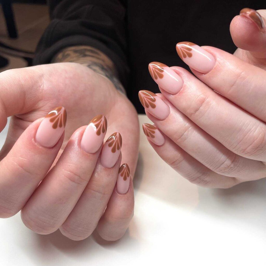 Short oval nails with a nude base and minimalist brown leaf line art, perfect for a subtle autumn-inspired look.