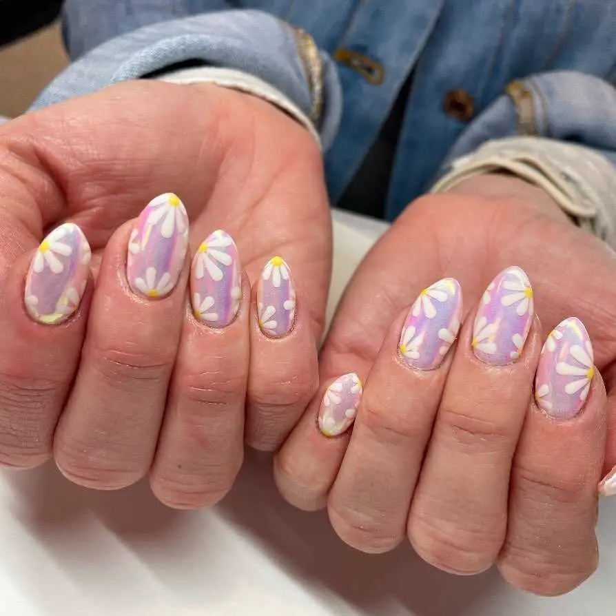 Almond-shaped nails with a lilac base and white petal designs, highlighted by yellow centers, evoking springtime blossoms.
