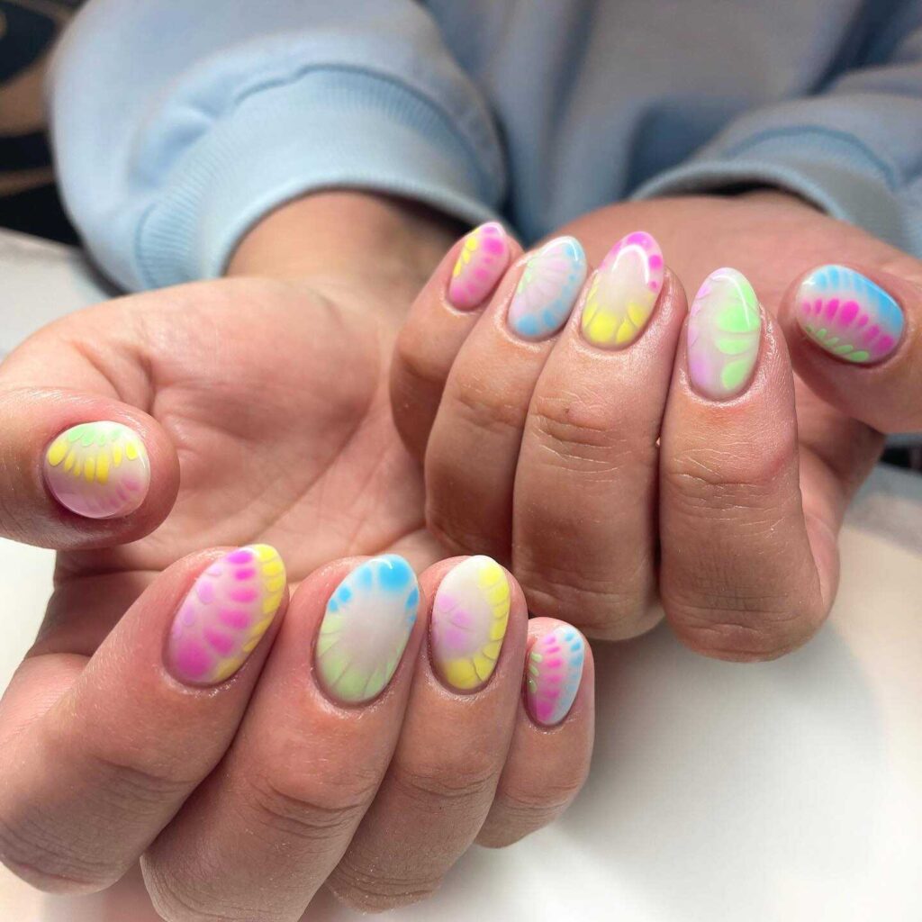 A set of nails adorned with a soft pastel watercolor design and bold pink and yellow accents, reminiscent of springtime blossoms.