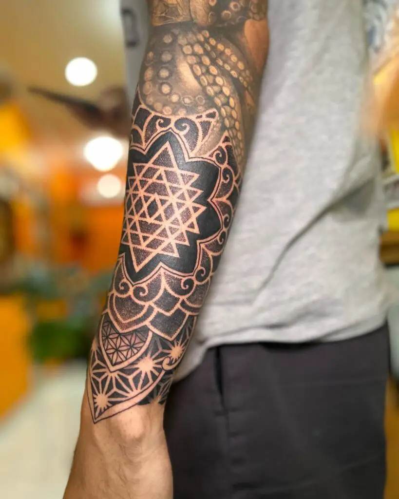 Close-up of a forearm mandala tattoo, emphasizing the fine dot shading and precision linework in the design.