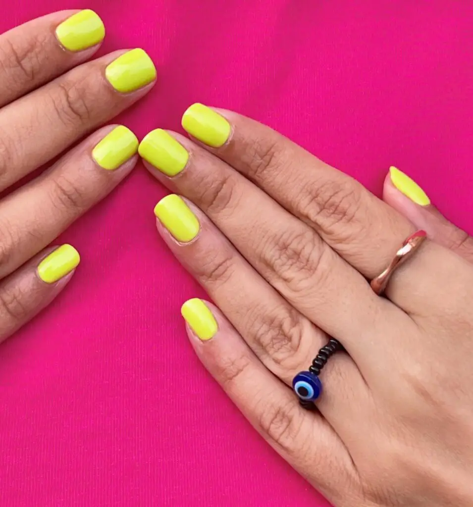 Fingers with a popping neon lime nail polish, offering a bold and vibrant touch to the hands adorned with silver jewelry.