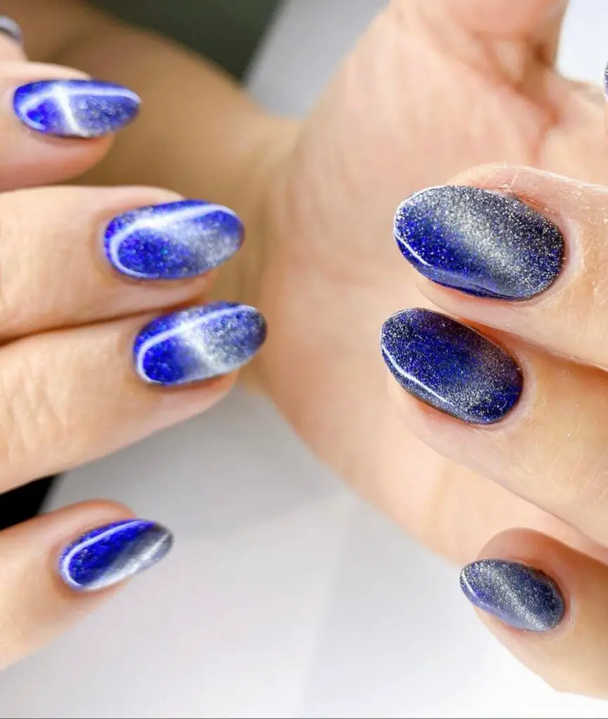 A hand with short nails painted in a glittering midnight blue polish, providing a rich and lustrous look.