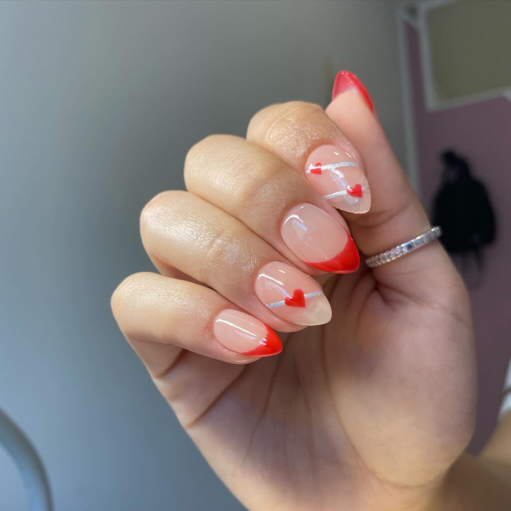 Lovestruck Tips: Transparent tips dotted with tiny red hearts bring a playful romance to the timeless French manicure, perfect for expressing affection.