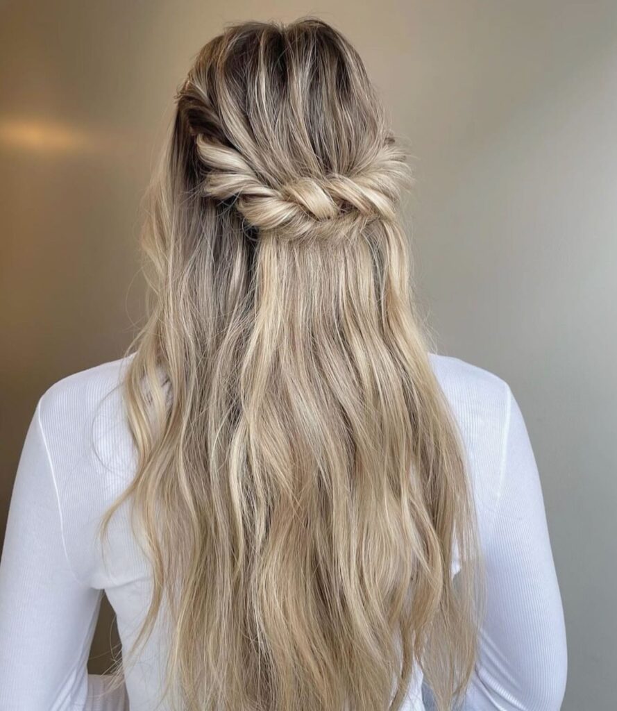 A sleek half-up knot with gentle waves, styled for a chic and modern prom appearance.