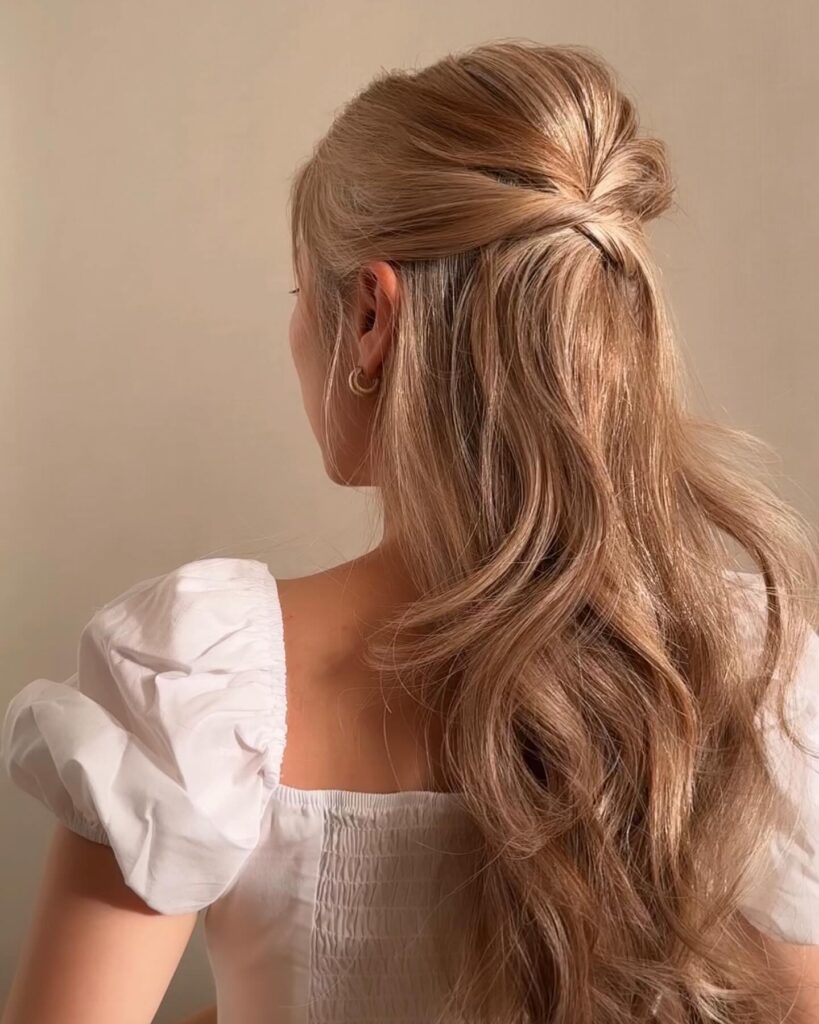 A classic half-up hairstyle with a twist, complemented by flowing dark curls for a timeless prom look.