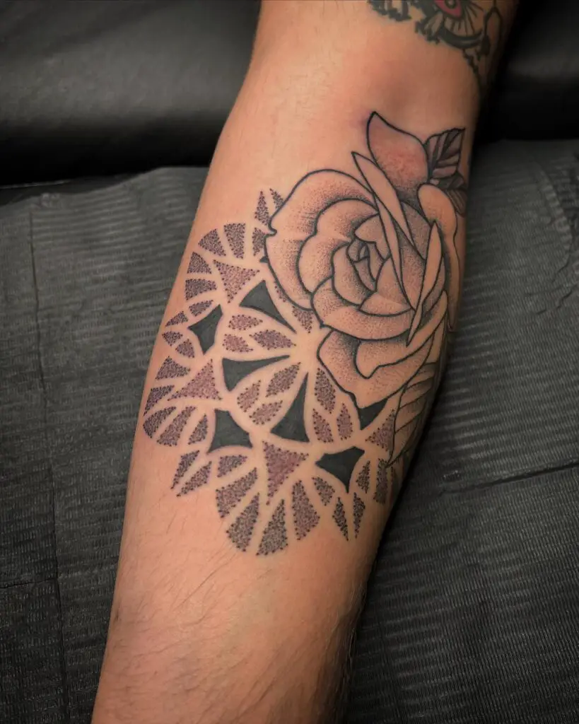 Forearm tattoo showcasing a combination of a blooming rose with mandala patterns.