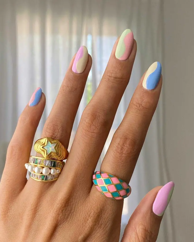 A hand with vibrant pastel nail art featuring a mosaic-like pattern in shades of blue, pink, and green.