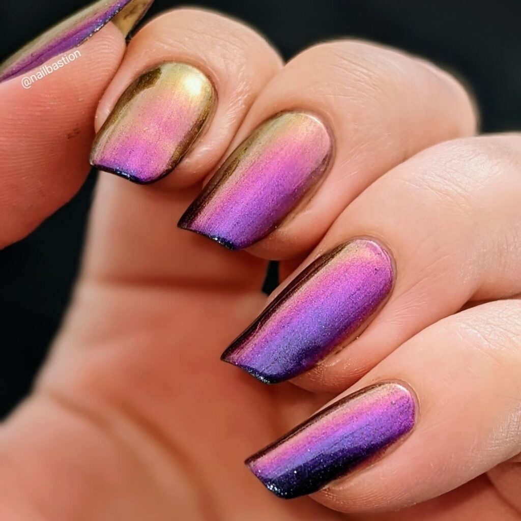Nails painted with an iridescent polish that shifts from golden to purple, capturing the essence of a sunset.