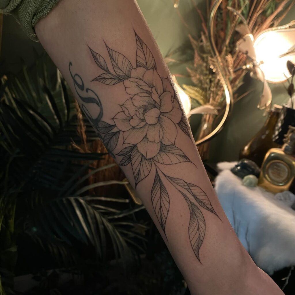 A forearm tattoo of a large, detailed flower and leaves, denoting natural beauty and growth.