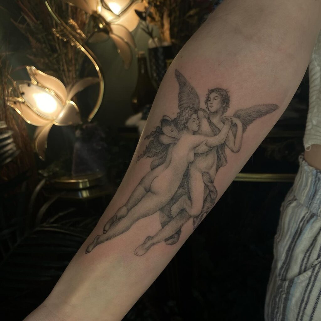 An arm tattoo of two angels dancing, capturing divine grace and connection.