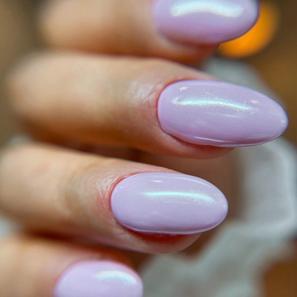 Close-up of nails coated in a soft lilac polish with a subtle sheen, embodying delicate sophistication.