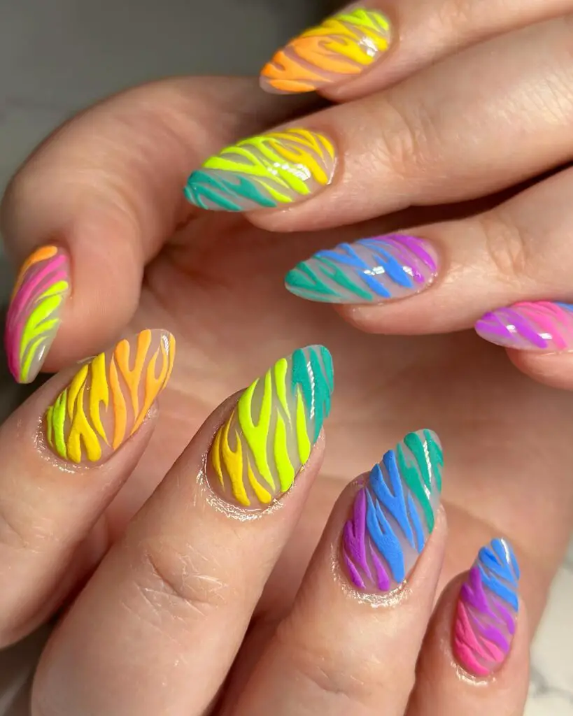 Fingertips flaunting almond-shaped nails with a vibrant mix of yellow, green, blue, and pink in a zebra-like pattern for a bold and tropical look.