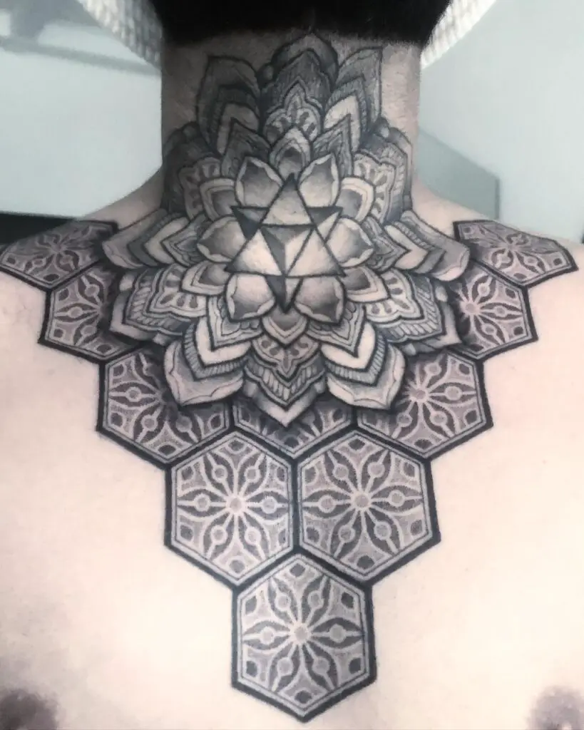 A bold mandala tattoo on the back of the neck, featuring intricate geometric patterns.