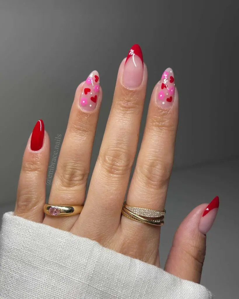 A hand with nails painted in vibrant red and adorned with heart patterns, perfect for adding a romantic twist to a springtime look.