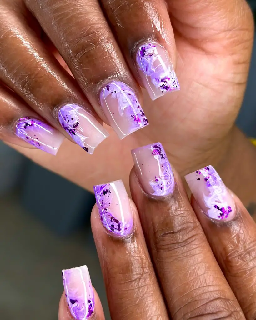Nails showcasing a transparent base with swirling purple marble designs, embodying an artistic and elegant aesthetic.