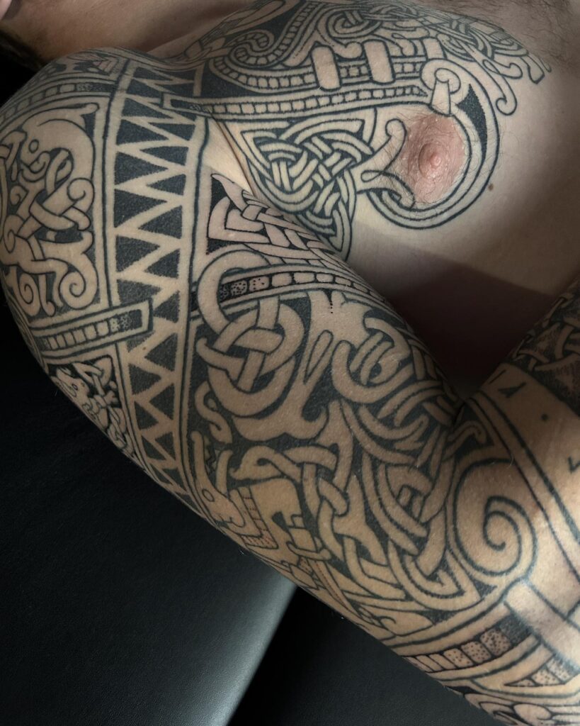 A tattoo depicting a Norse warrior shield with surrounding runes, symbolizing protection and strength.