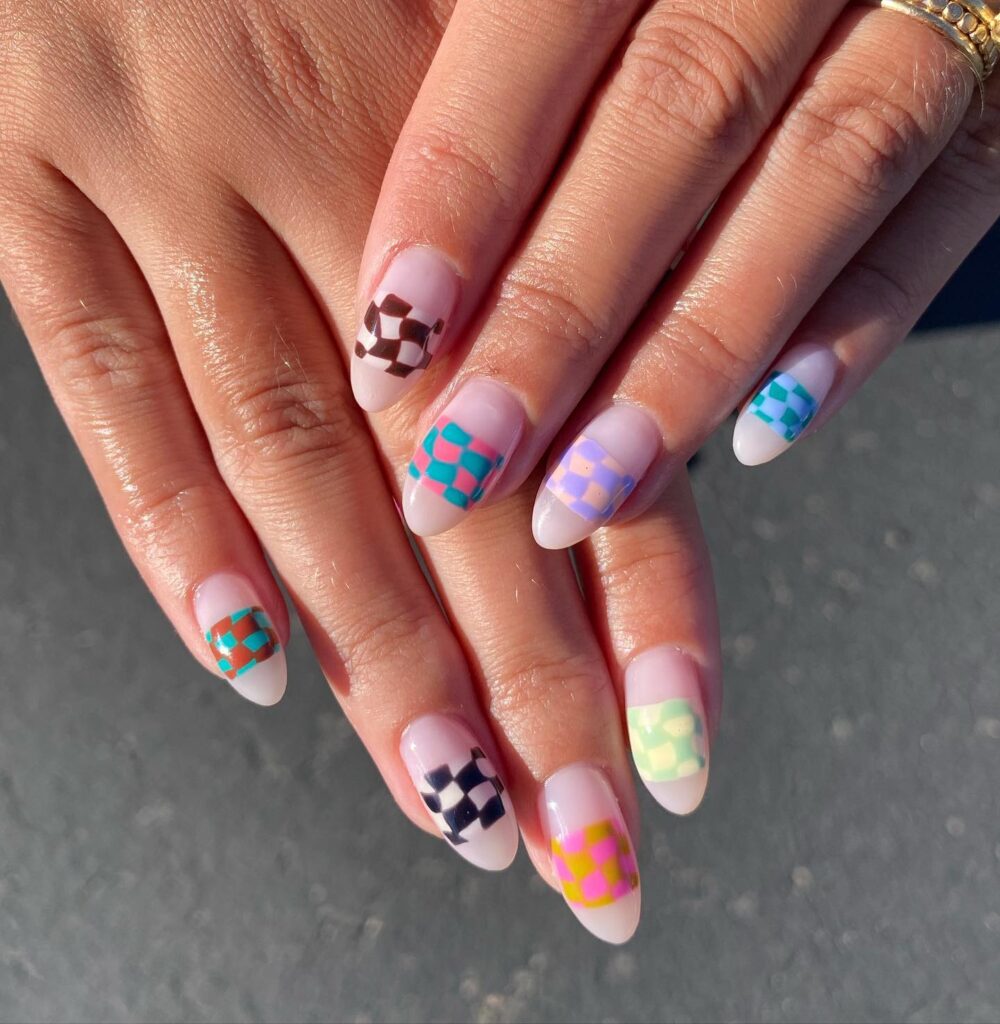 A hand featuring nails adorned with abstract geometric patterns in a playful pastel color scheme on a sheer base.