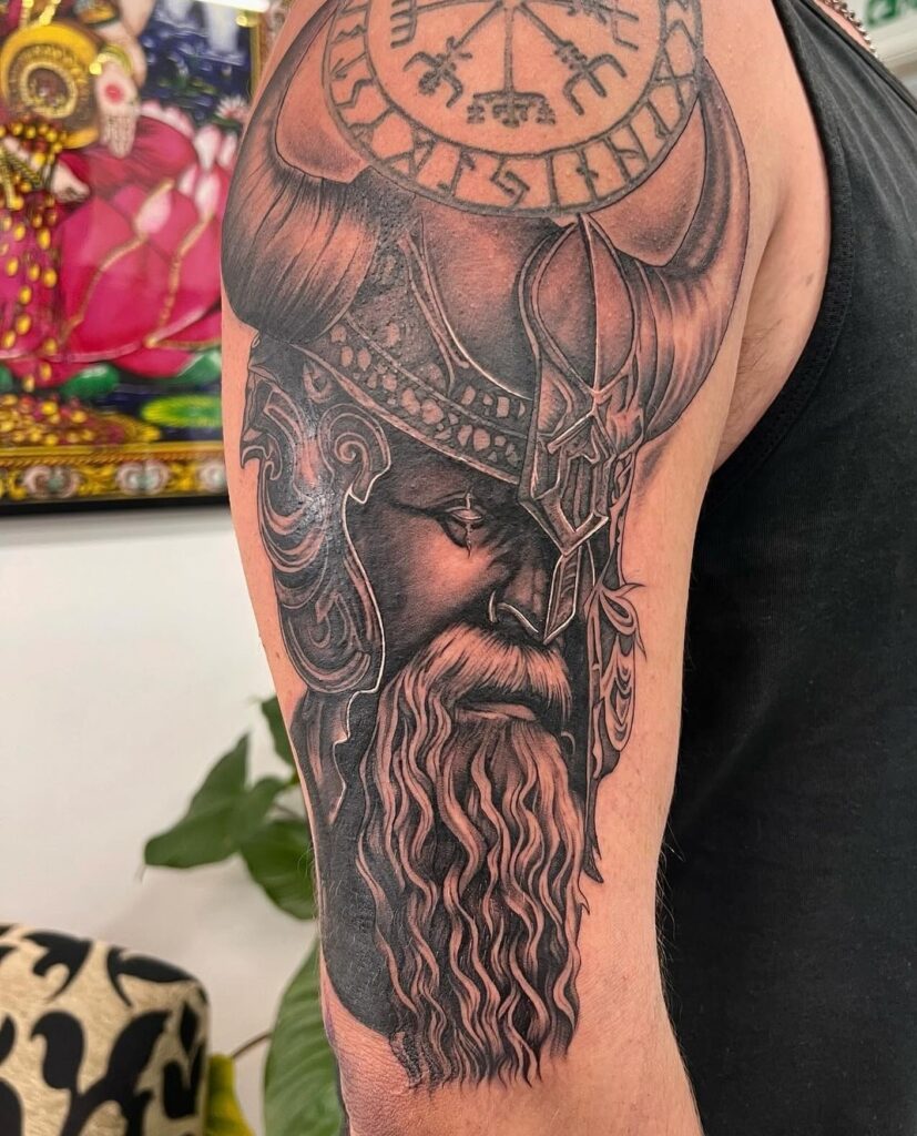 A detailed tattoo of a Norse warrior with a Vegvísir symbol on his helmet and a realistic beard.