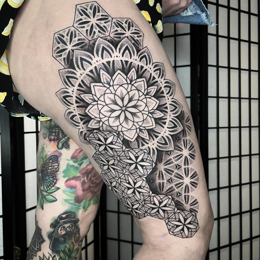 A half-sleeve tattoo showcasing a large floral mandala transitioning into geometric patterns on the arm.