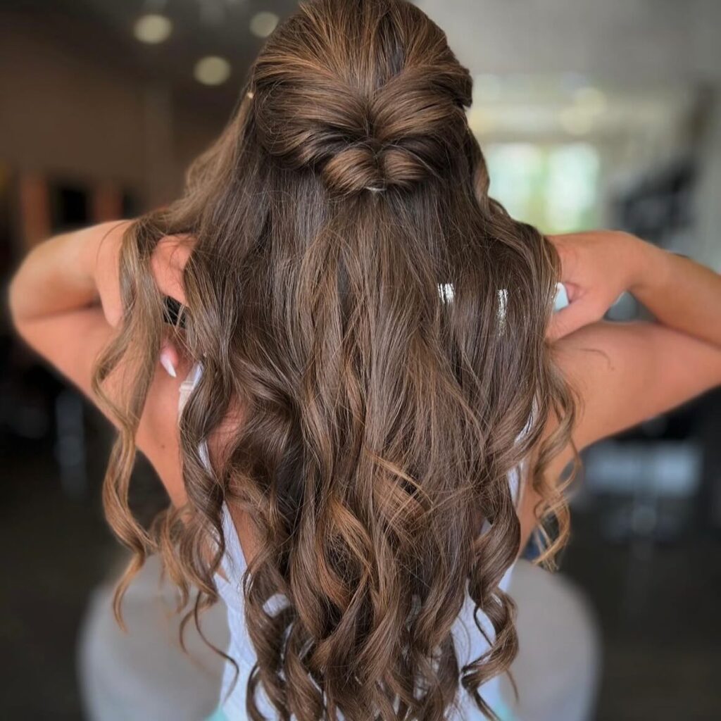 A chocolate swirl half-up hairstyle with elegant curls, suitable for a sophisticated prom night appearance.