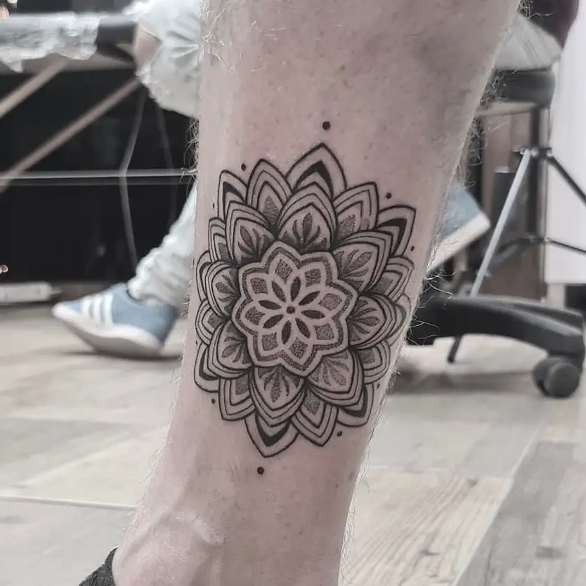 A lotus mandala tattoo on the ankle with detailed linework and dot shading.