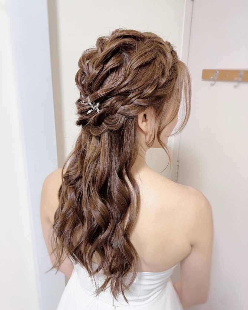 A detailed braid with a jeweled accessory set against waves, creating a romantic prom hairstyle with a hint of sparkle.