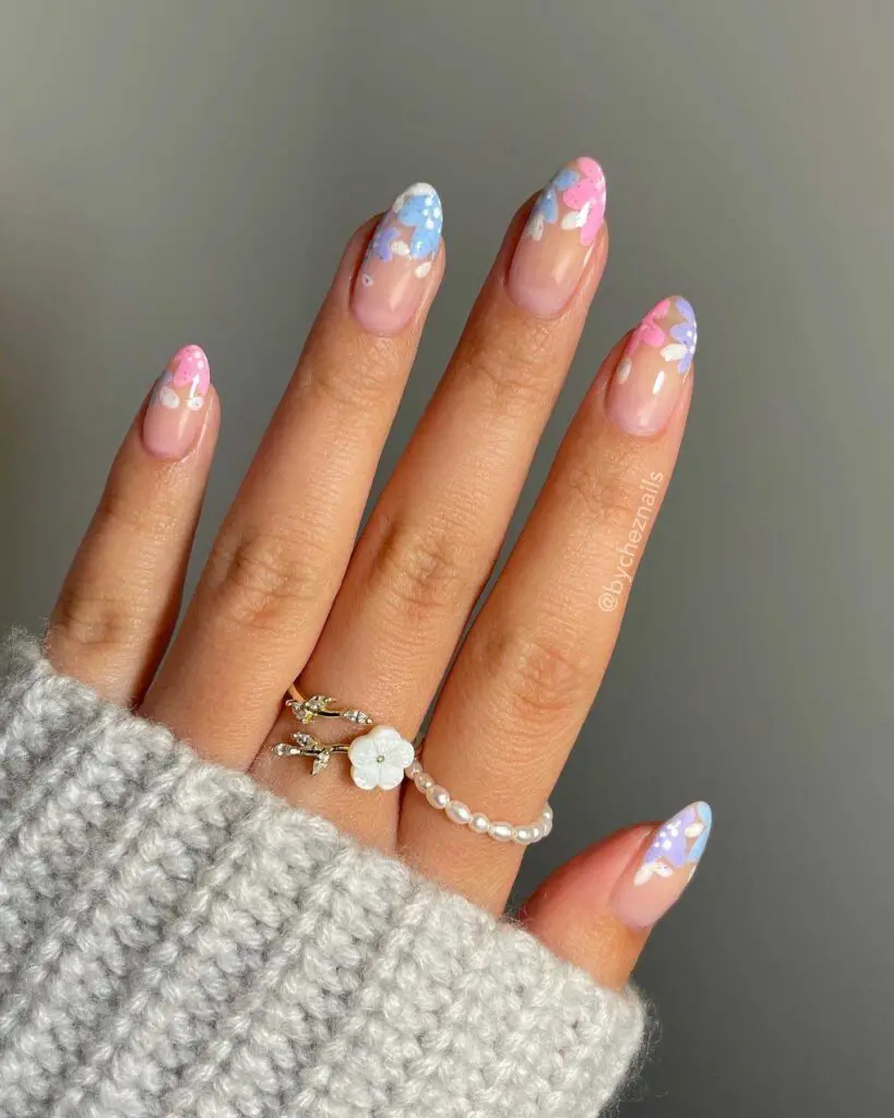 Hand with nails painted to evoke pastel clouds and cherry blossoms, perfect for a serene and whimsical spring manicure.