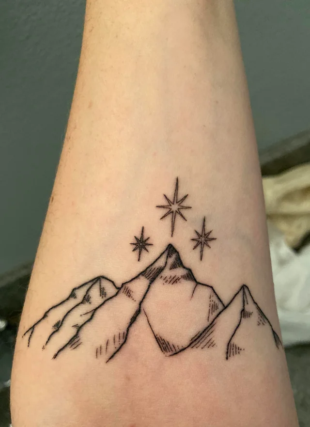 A tattoo of geometric mountains encircled by the quote "To the stars that listen and the dreams that are answered," signifying a harmony of dreams and reality.