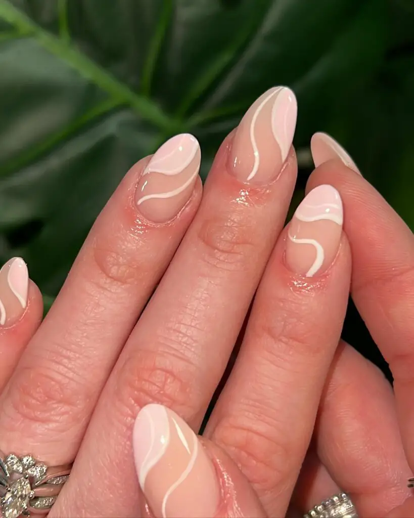Close-up of a hand with long nails painted with white abstract swirls on a sheer base, evoking a sense of elegance and modernity.