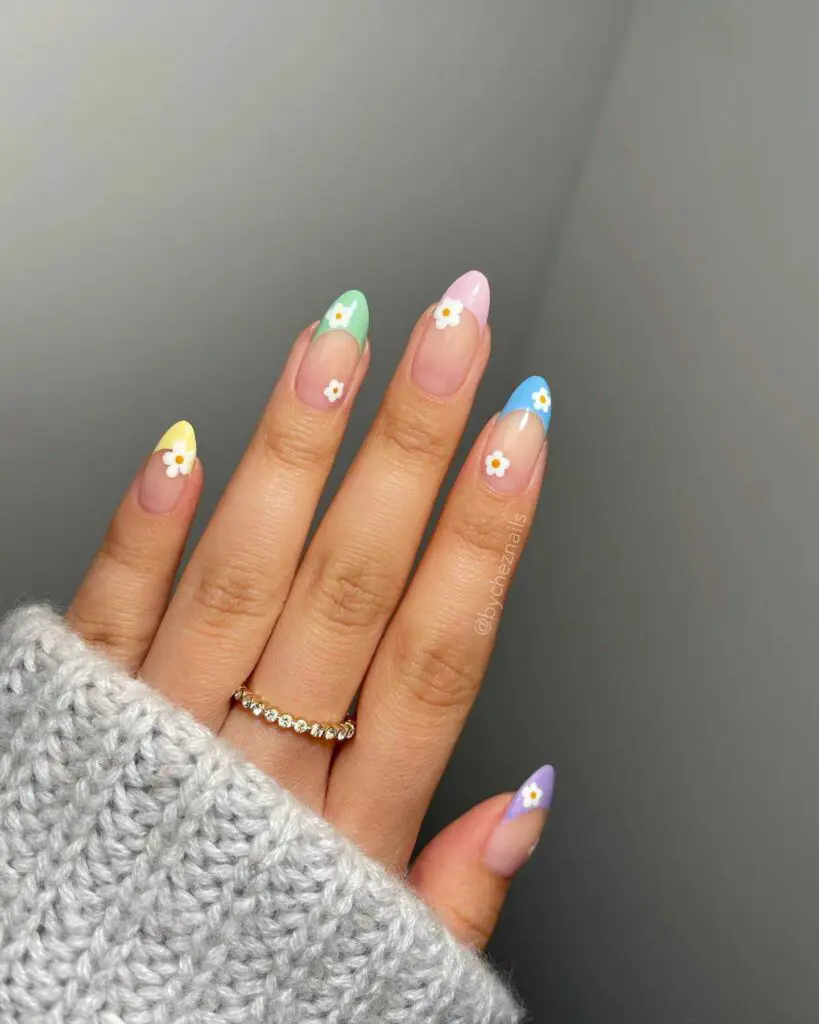 Hand with nails decorated with a confetti of pastel dots and flower accents, perfect for a festive and playful spring celebration.