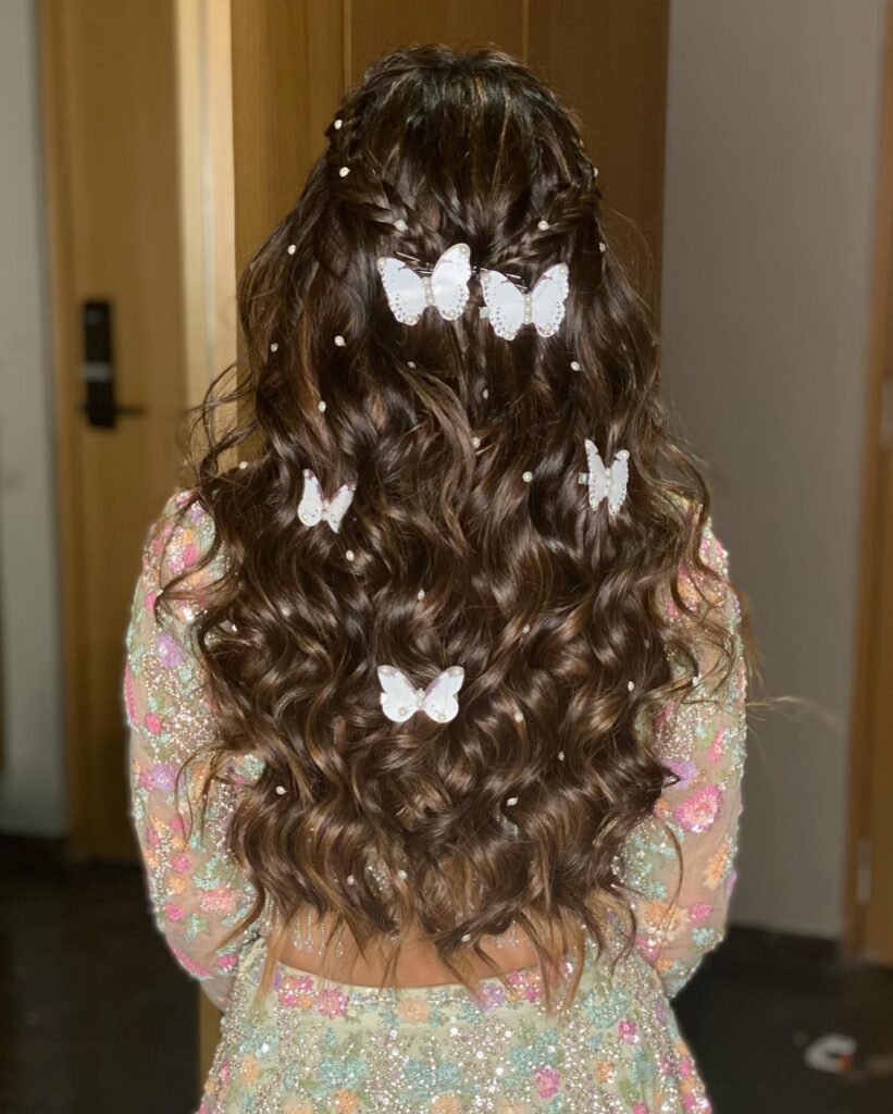 Brunette hair in a half-up style with soft waves, decorated with white butterfly clips and small pearls, perfect for prom.