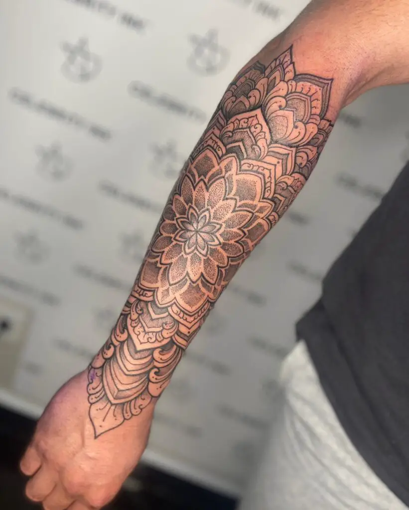 A forearm tattoo with a floral mandala design in rich black ink, showcasing depth and natural elements.
