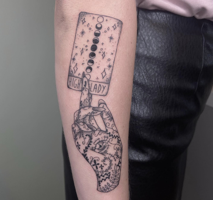 An arm tattoo styled like a tarot card named "High Lady," with celestial and intricate patterns, symbolizing empowerment and mysticism.