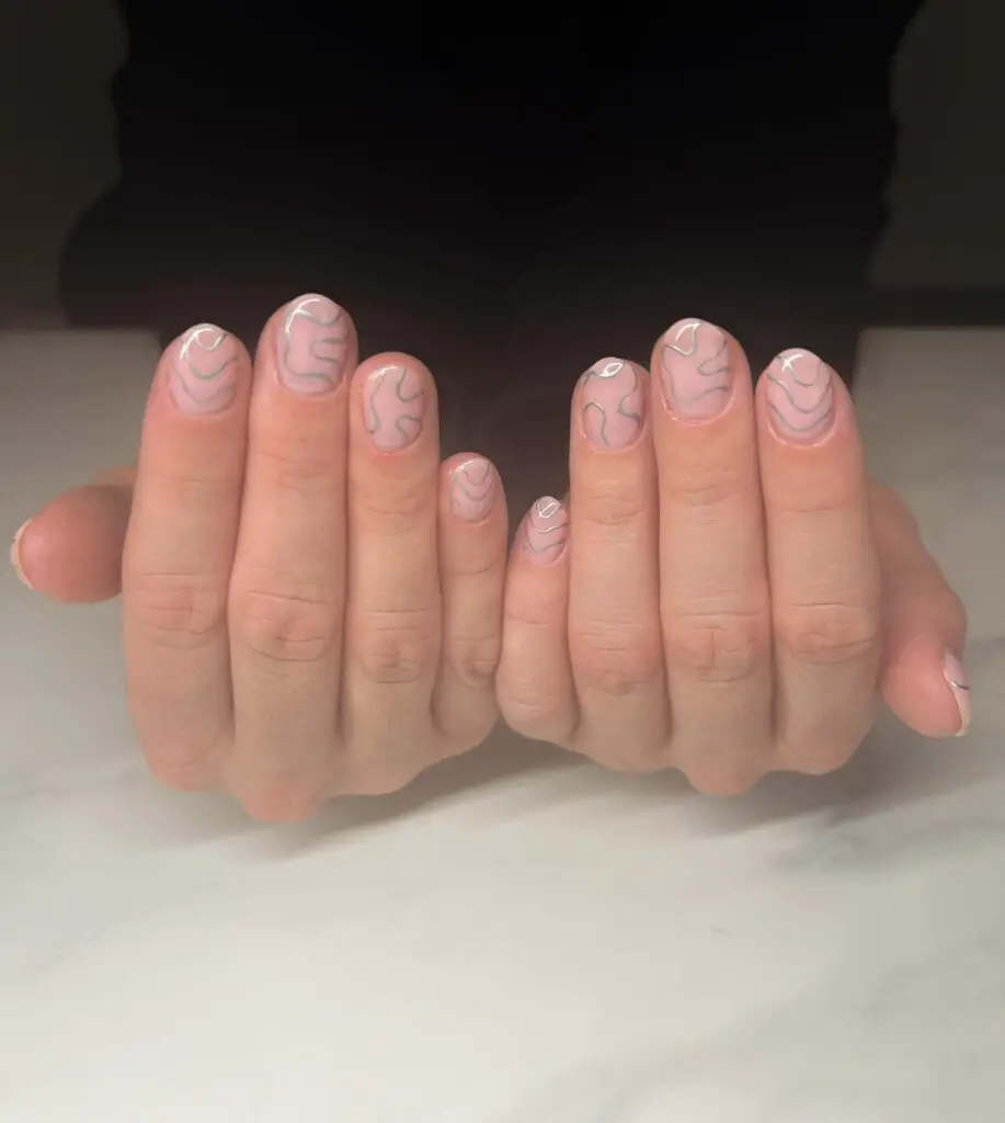 Hands with nails showcasing a delicate pink marble design, giving off a refined and elegant vibe against a soft, glowing backdrop.