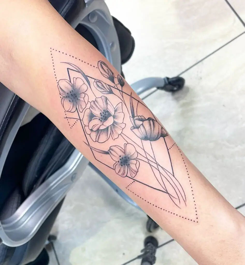 An outline of a floral tattoo within a diamond-shaped border on an arm, featuring stencil-style flowers and dotted line accents.