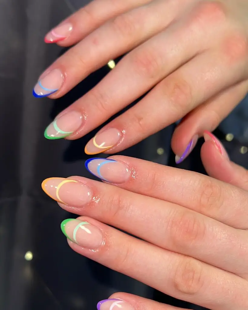 A set of oval-shaped nails displaying a French manicure with rainbow-colored tips, creating a fun and vibrant look.