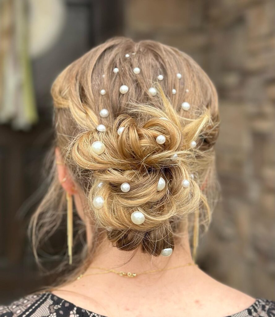 Intricate low bun updo embellished with pearls, a sophisticated hairstyle choice for prom.