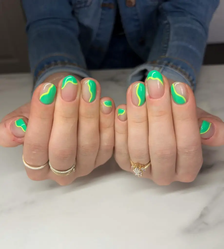 A set of hands with nails displaying an abstract design of bright green swirls on a nude base, offering a fresh and artsy look.