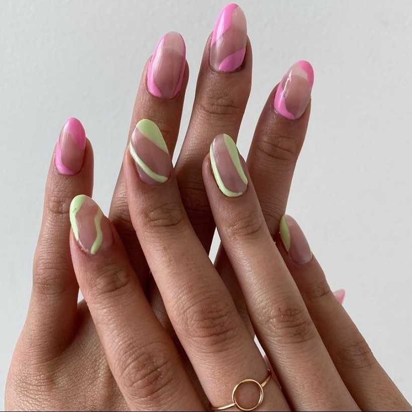 A hand showing off almond-shaped nails with pink and green wavy lines, a creative take on the elegant French manicure.