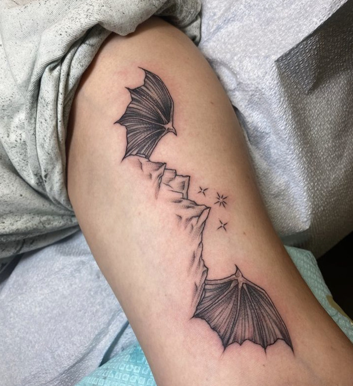 A tattoo of bats flying from mountain peaks, representing change and the freedom of exploration.