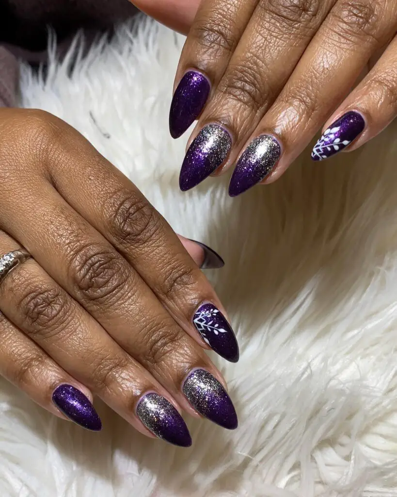 Stiletto nails with a glittery purple base, some adorned with silver glitter and others with white cosmic patterns, evoking a starry night sky.