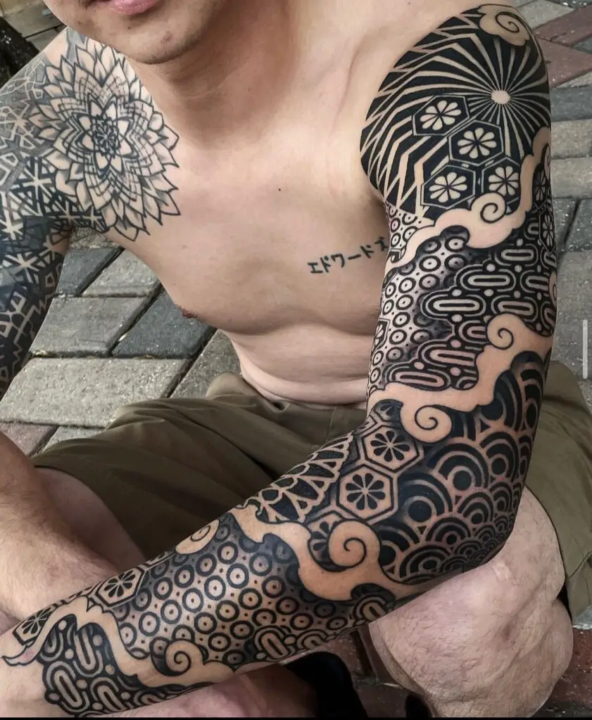 Full-sleeve tattoo with a variety of abstract and traditional patterns in black ink, emphasizing the use of negative space.