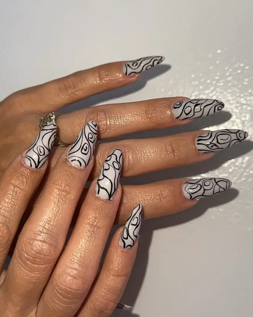 Long stiletto nails with a sophisticated black and white abstract pattern, offering a chic monochrome look.