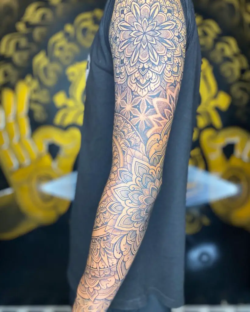Full arm tattoo of detailed geometric mandala designs with precise patterns in black and gray shades.